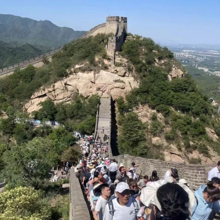 Visitors climbing a steep, crowded section of the Great Wall towards a watchtower