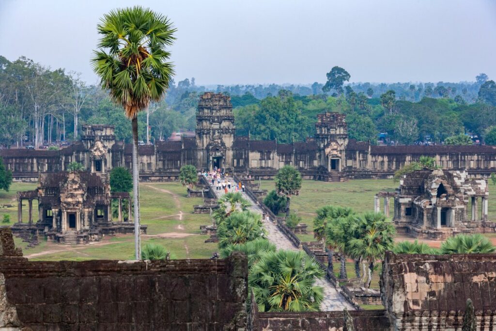 Elevated view of an Angkor temple complex near Angkor Wat, with a long central walkway, stone gateways and palm trees