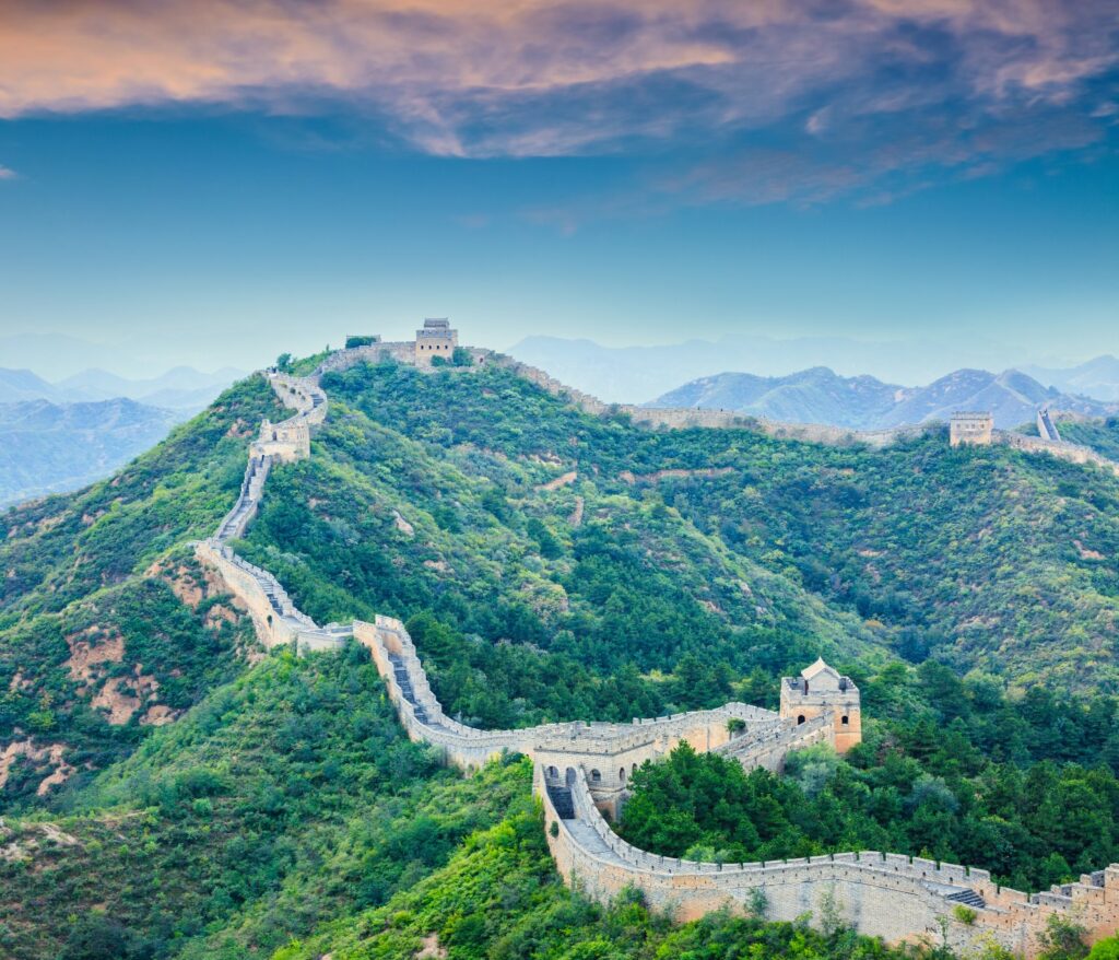 The Great Wall of China winding across green mountain ridges, with watchtowers along the route