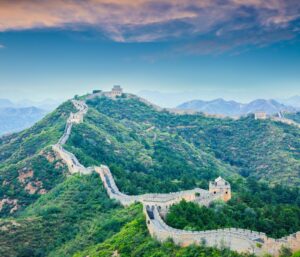 The Great Wall of China winding across green mountain ridges, with watchtowers along the route