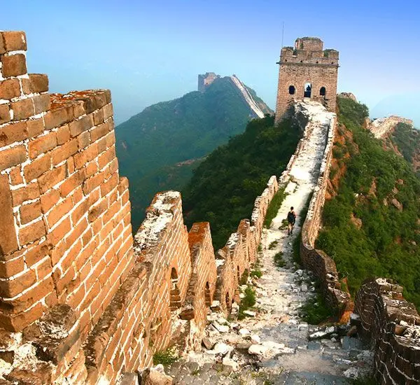 Weathered Great Wall path leading to a watchtower on a steep mountain ridge