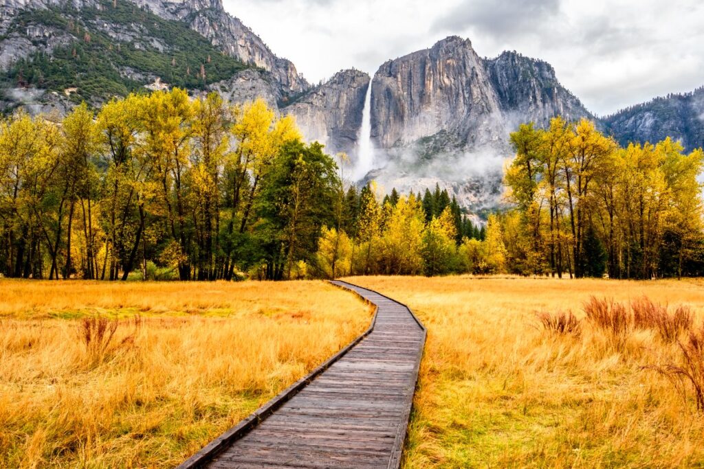 Boardwalk through Yosemite Valley with waterfall and granite cliffs