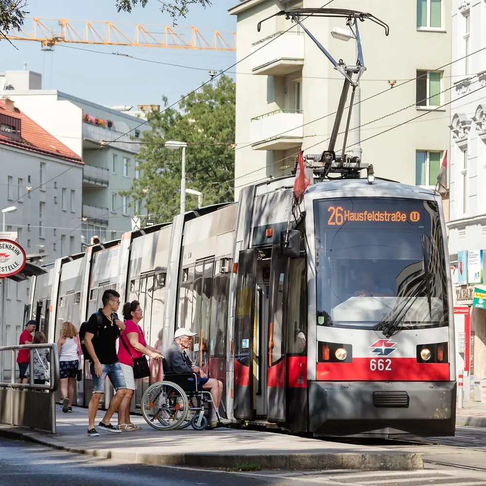 Wheelchair user beside a tram at a stop in Vienna, Austria