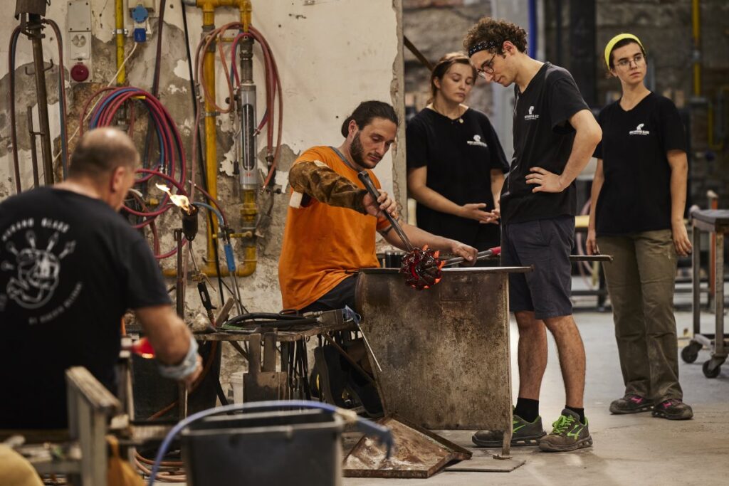 Murano glassmaker shaping molten glass inside a workshop