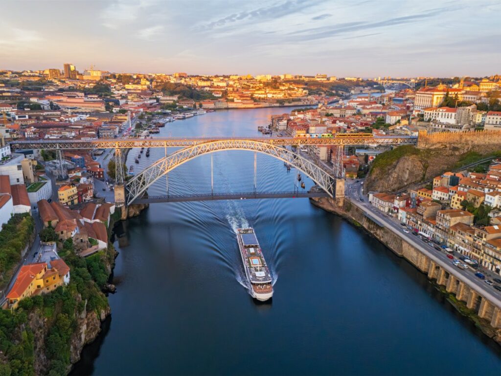 River cruise boat passing beneath the Dom Luís I Bridge on the Douro River in Porto