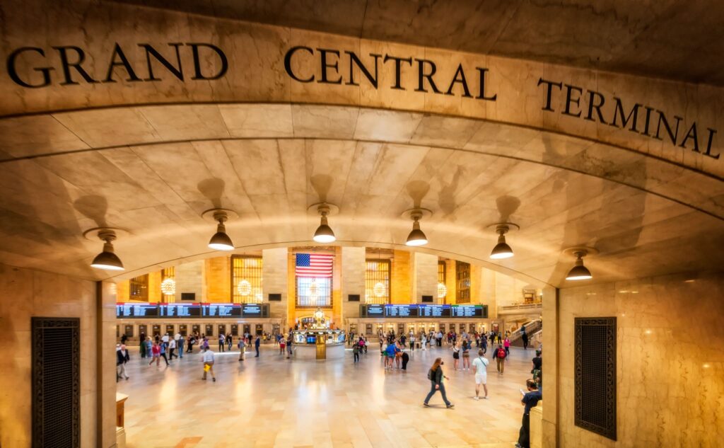 View through the Grand Central Terminal entrance arch into the Main Concourse, where travellers pass the central information booth