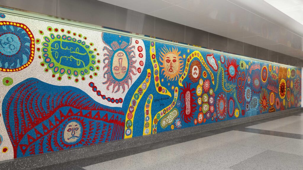 Colourful mosaic mural with faces and abstract shapes along a corridor at Grand Central Madison.