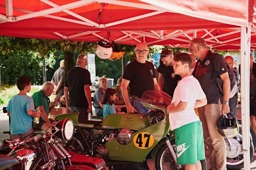 Families and motorcycle enthusiasts viewing historic Moto Guzzi motorcycles in Mandello del Lario