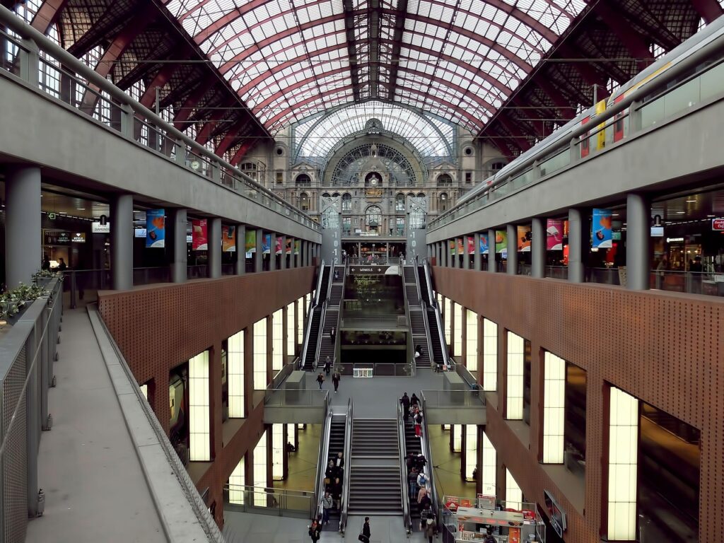 Antwerp Central Station’s multilevel atrium, with escalators connecting the floors beneath the arched steel and glass roof.